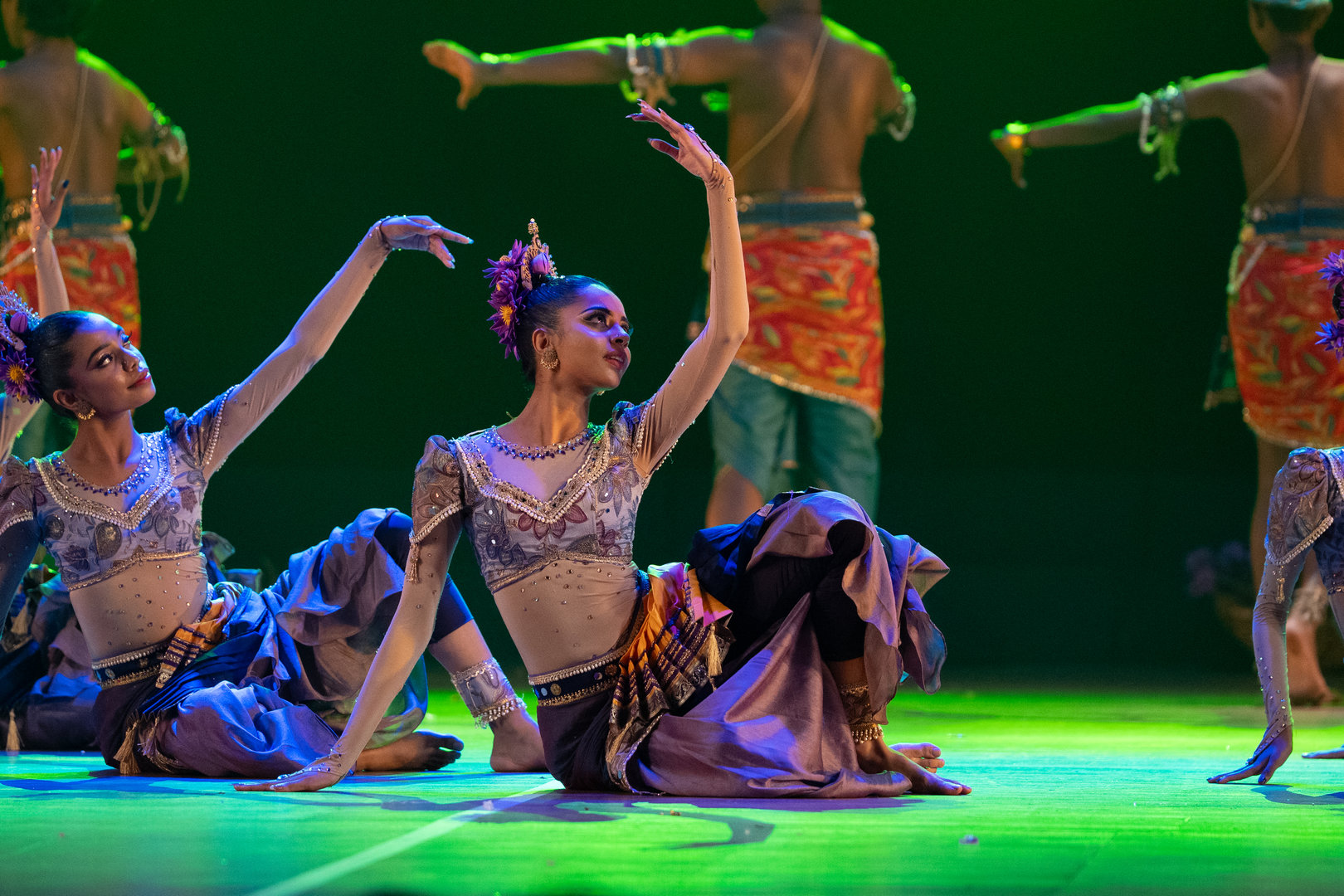 Mystical Traditional Dance Performance in Vibrant Green Lighting Traditional dancers in ornate costumes perform synchronized moves on stage under vivid green lighting.