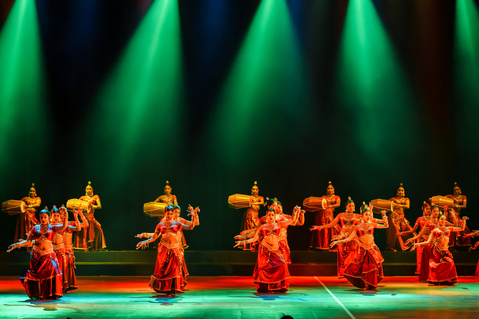 Grand Indian Dance Performance With Live Drummers and Lights Indian dancers in red and gold performing traditional dance on stage with live drummers and colorful lights.
