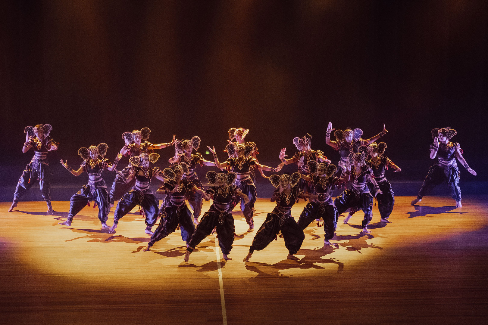 Dynamic Ganesha Dance Troupe Under Dramatic Stage Lighting Troupe in elephant-inspired costumes performs synchronized Ganesha dance on dramatically lit stage.