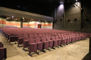 Modern Auditorium with Tiered Purple Seats and Stage Lighting Modern auditorium with purple seats, tiered seating, stage lighting, and spacious, contemporary interior design.